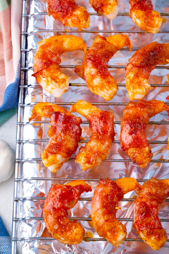 Overhead shot of crispy bacon wrapped shrimp with brown sugar on a wire rack.