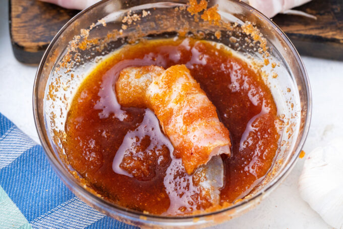 Dipping bacon wrapped shrimp in brown sugar mixture.