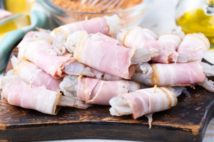 Bacon wrapped shrimp on a cutting board.