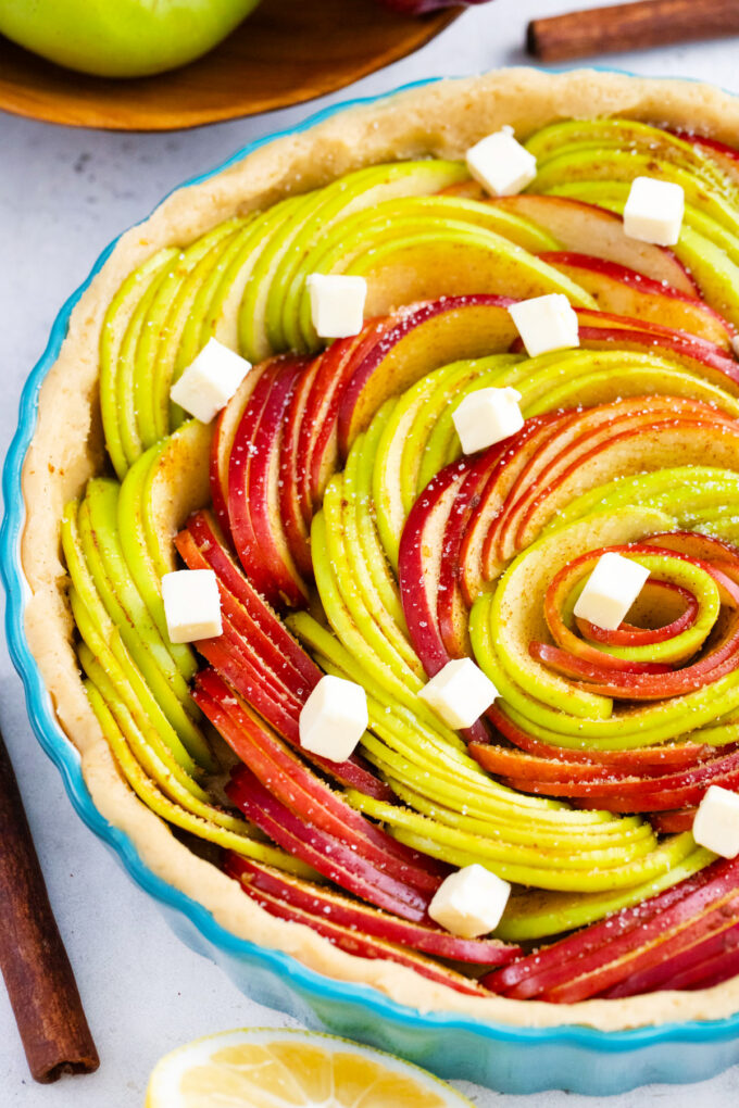 Overhead shot of apple tart in a rose pattern topped with pieces of batter.