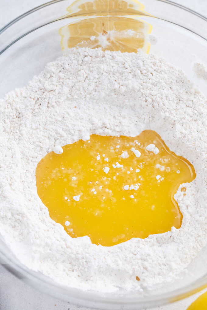 Adding melted butter to a bowl with flour.