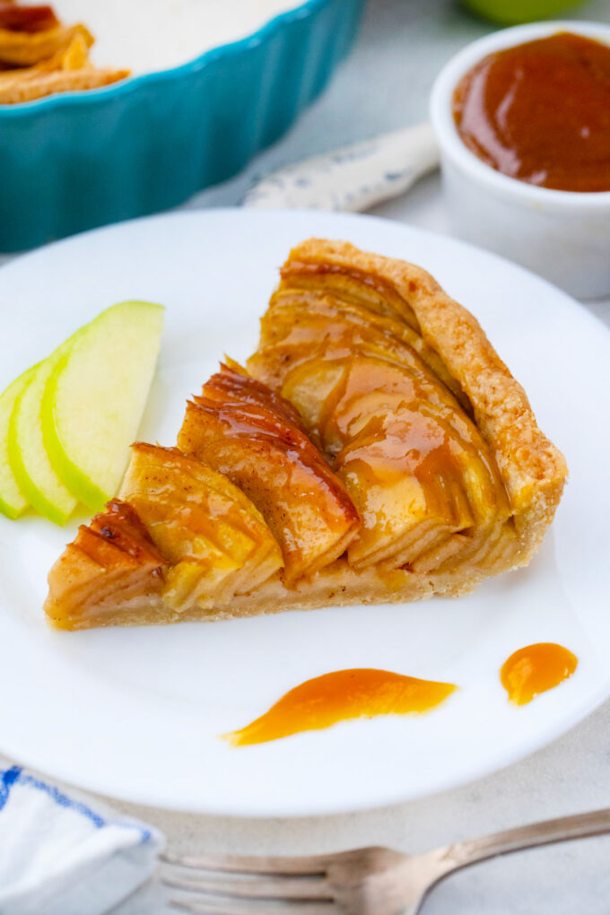 Apple tart slice served with caramel sauce.
