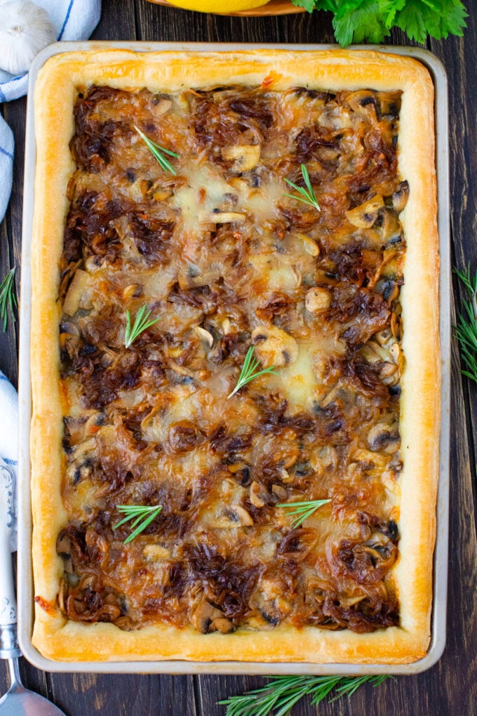 Overhead shot of caramelized onion tart with mushrooms on puff pastry.