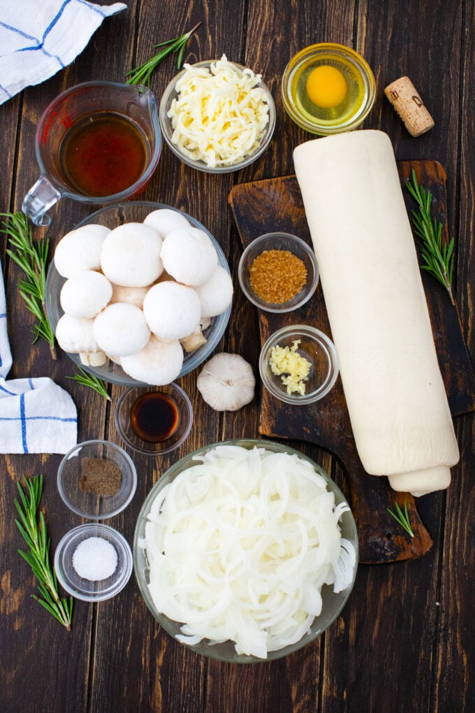 Overhead shot of caramelized onion tart ingredients on a wooden table.