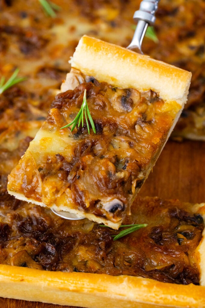 A slice of caramelized onion tart with mushrooms.