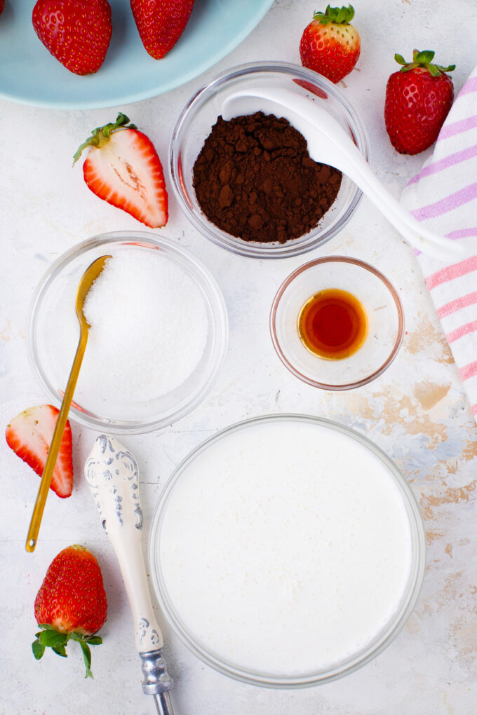 Overhead shot of chocolate whipped cream ingredients in bowls on a table.