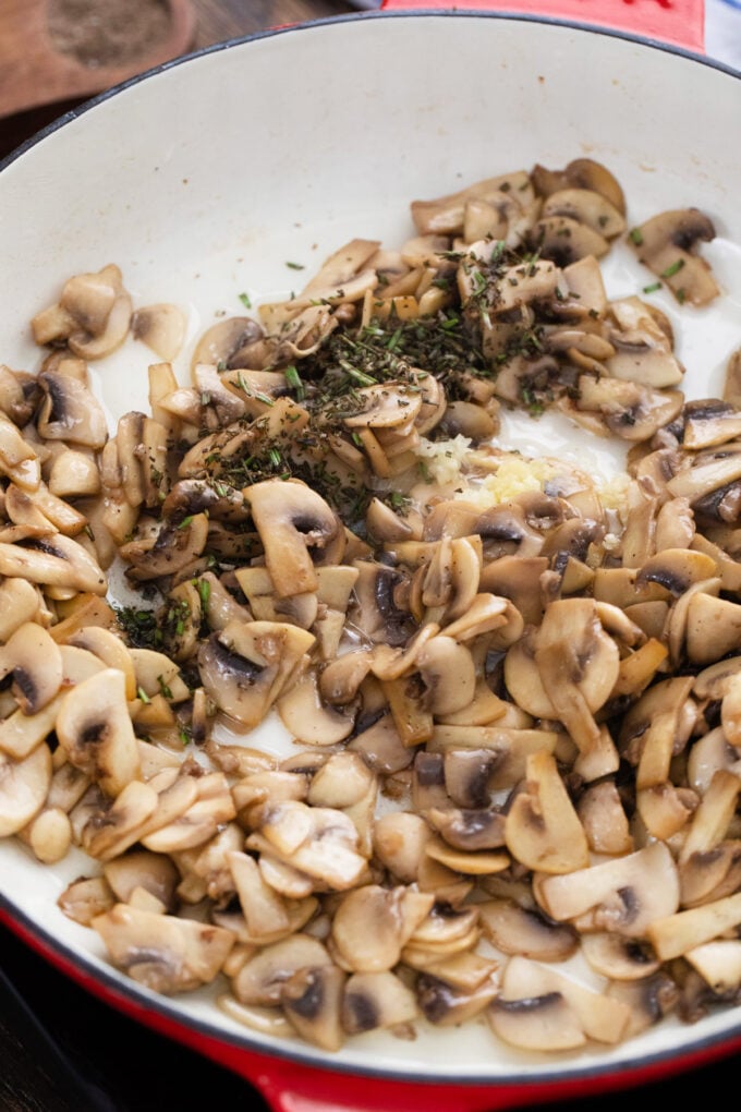 Sautéing mushrooms and herbs in a skillet.