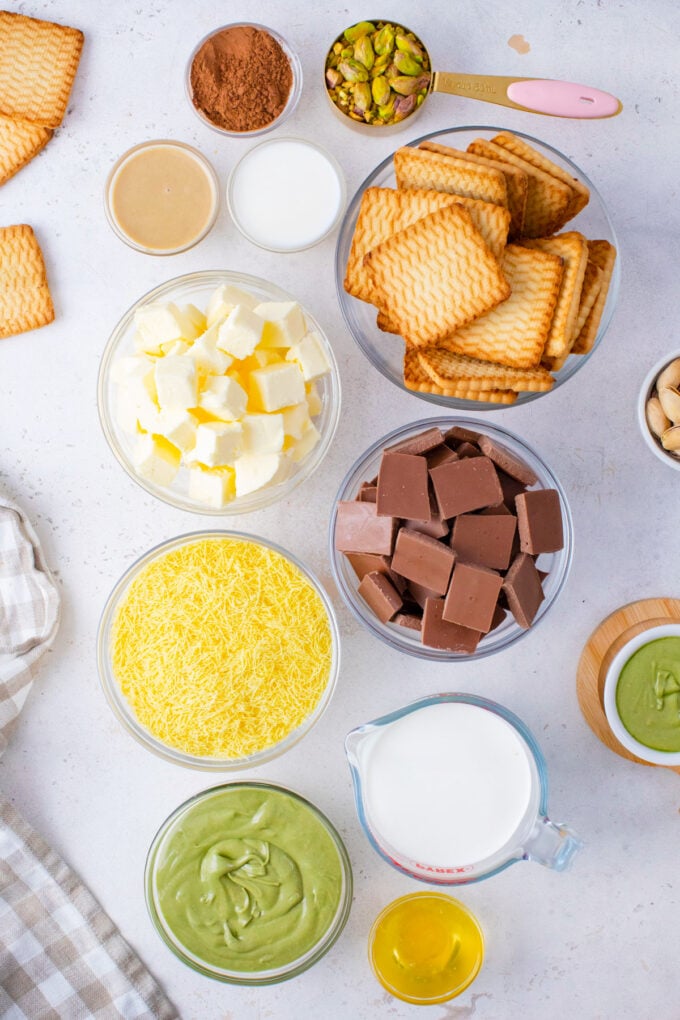 Overhead shot of Dubai chocolate tart ingredients in bowls on a white surface.