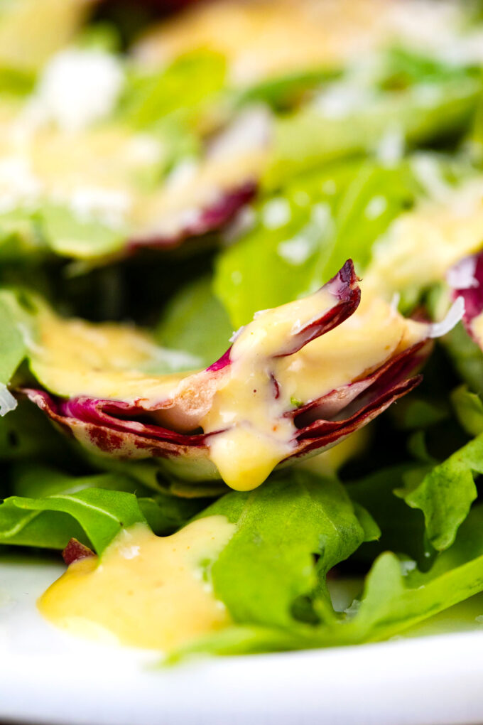 Close shot of honey mustard sauce on salad green.