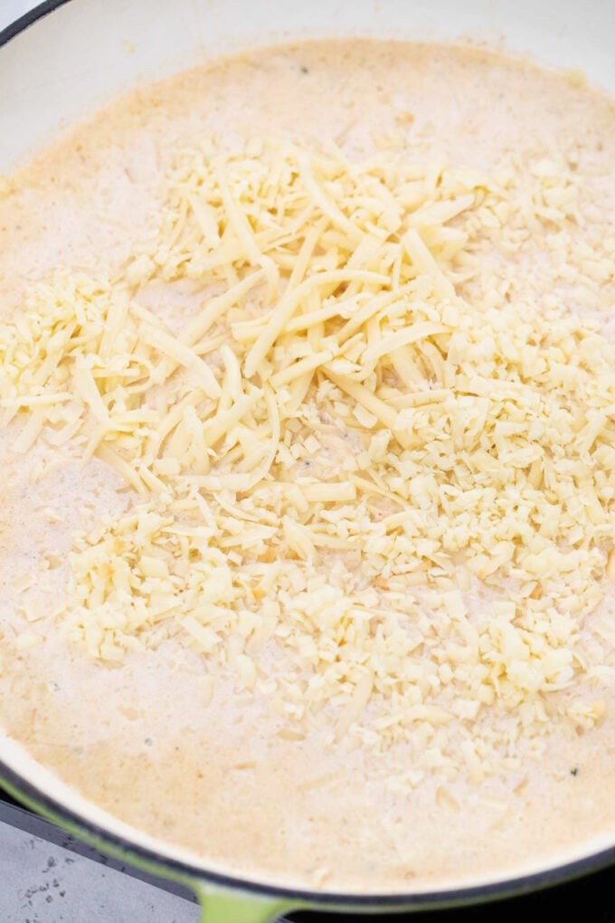 Adding cheese to mac and cheese sauce.