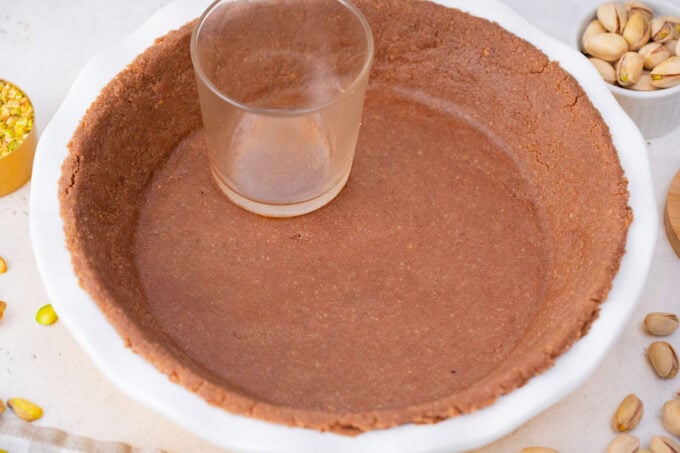 Pressing chocolate graham crust into a pie dish.