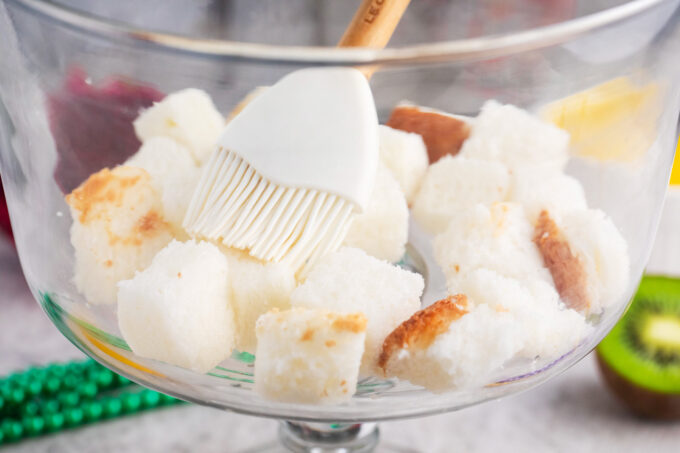Brushing angel's food cake cubes with simple syrup.