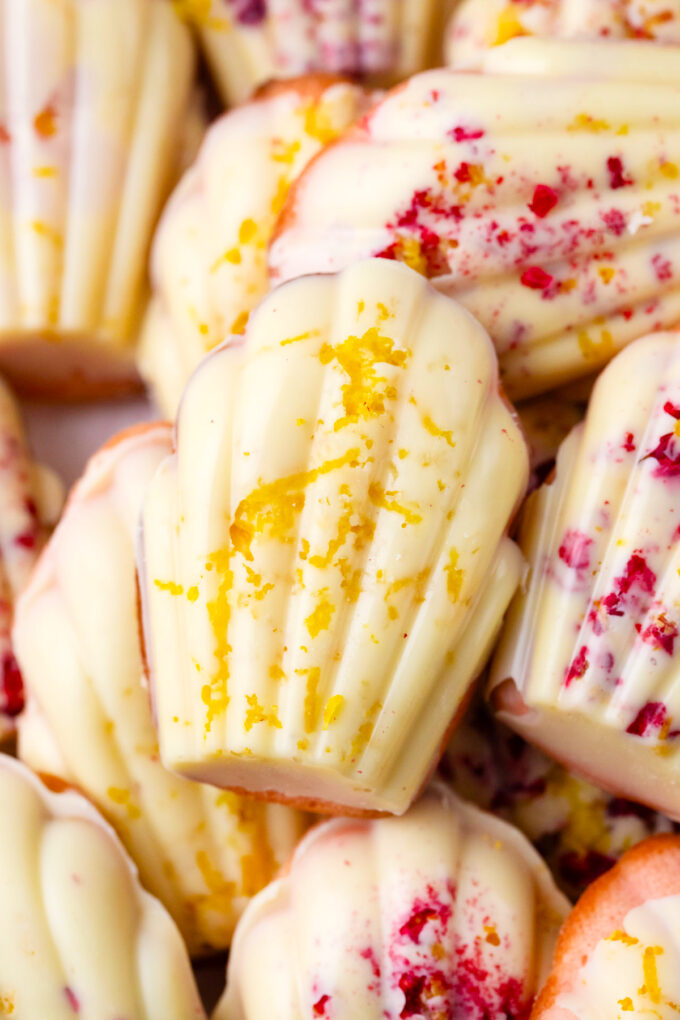 Strawberry madeleines topped with white chocolate and lemon zest.