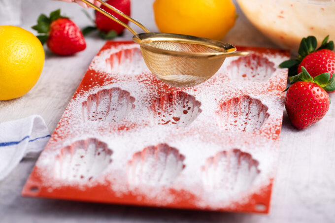Sprinkling a madeleine tray with flour.
