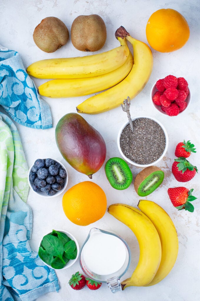 Overhead shot of rainbow chia pudding parfaits ingredients arranged on a white surface.