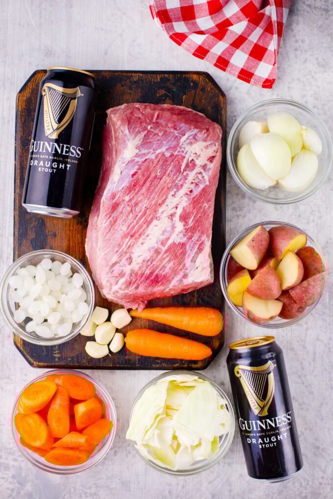 Overhead shot of Dutch oven corned beef with Guinness beer ingredients arranged on a table.