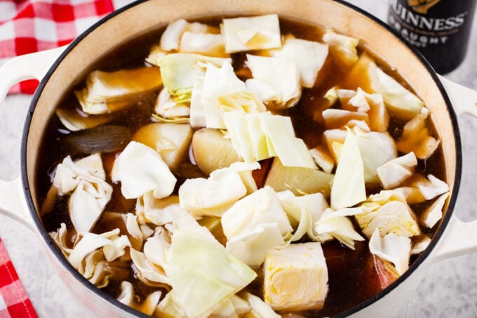 Adding chopped cabbage to homemade Dutch oven corned beef.