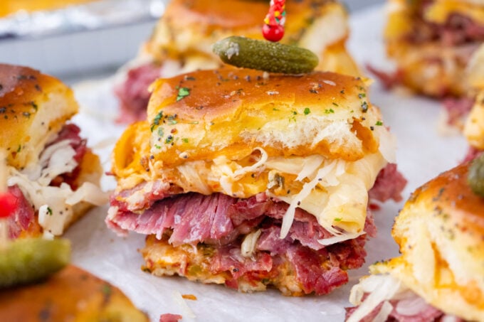 Homemade corned beef sliders topped with mini pickle.