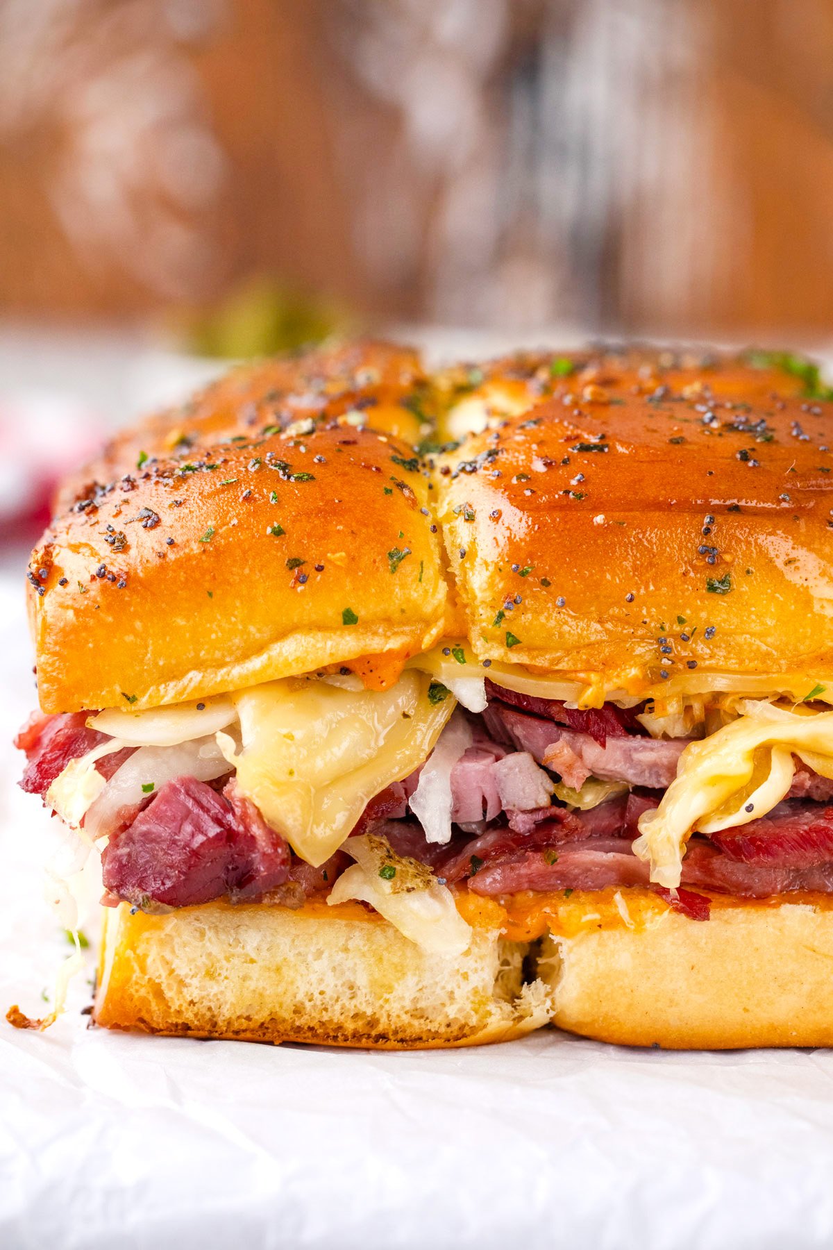 Cheesy corned beef sliders topped with poppy seed butter sauce.