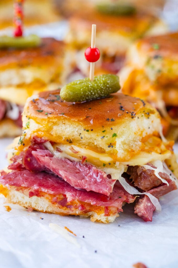 Reuben sliders topped with mini pickle.