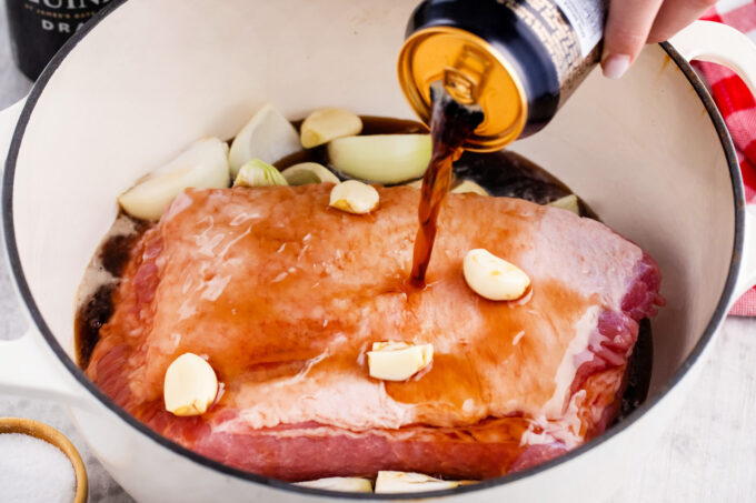 Adding Guinness beer to a pot with corned beef brisket.