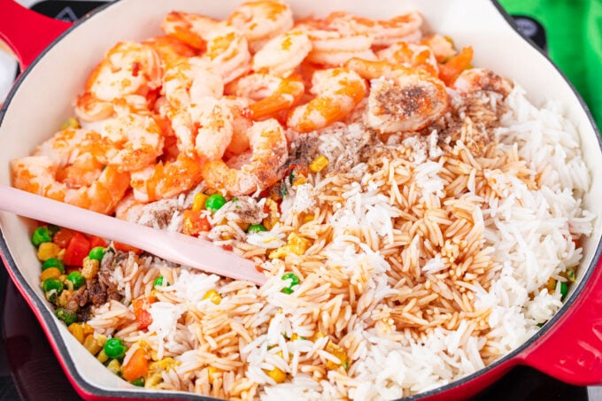 Adding cooked shrimp and rice to the pan for shrimp fried rice.