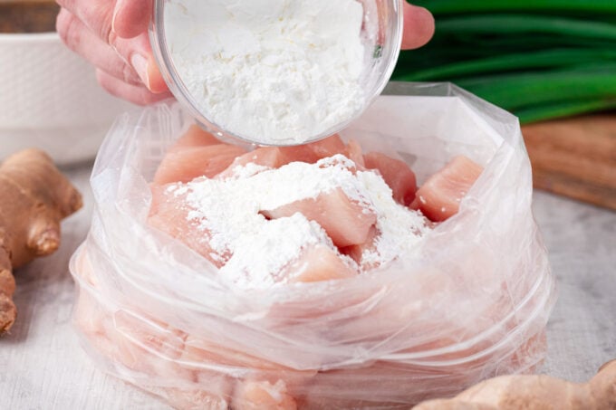 Coating chicken pieces in cornstarch.