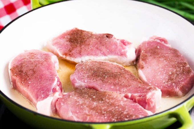 Searing seasoned pork chops in a pan.