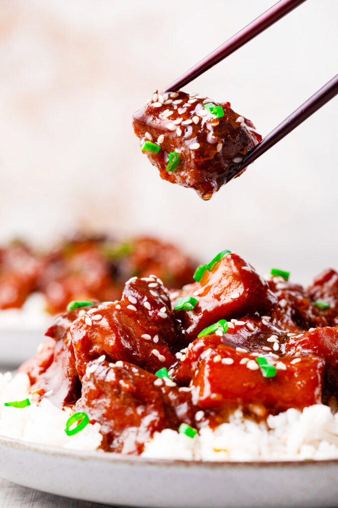 Sticky slow cooker sesame chicken pieces over rice.