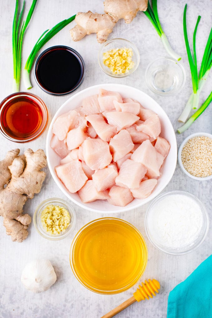 Overhead shot of slow cooker sesame chicken recipe ingredients in bowls on a table.