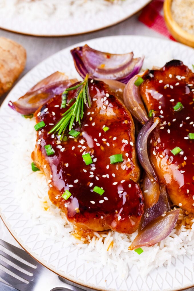 Homemade General Tso pork chops with red onions over white rice.