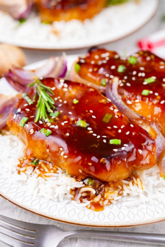 General Tso sauce pork chops with red onions, sesame seeds, and chopped green onions.