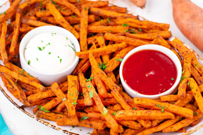 Crunchy air fried sweet potato fries with ketchup and white sauce.