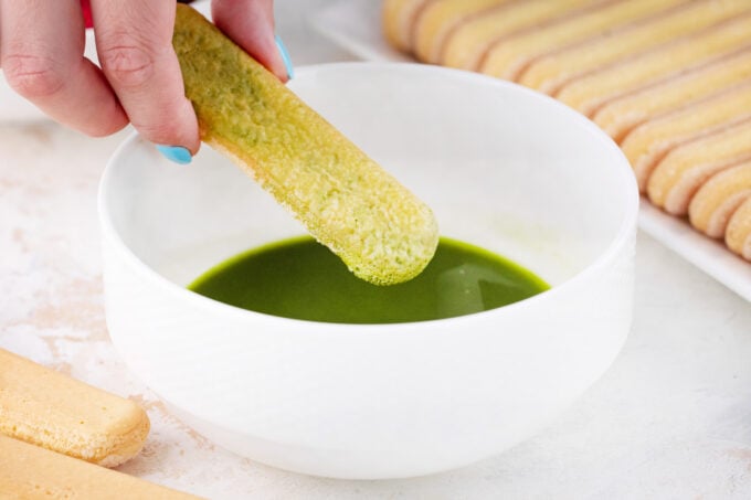 Dipping ladyfingers cookies into matcha mixture.