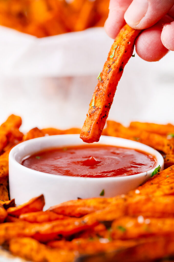 Dipping air fried sweet potato fry in ketchup.