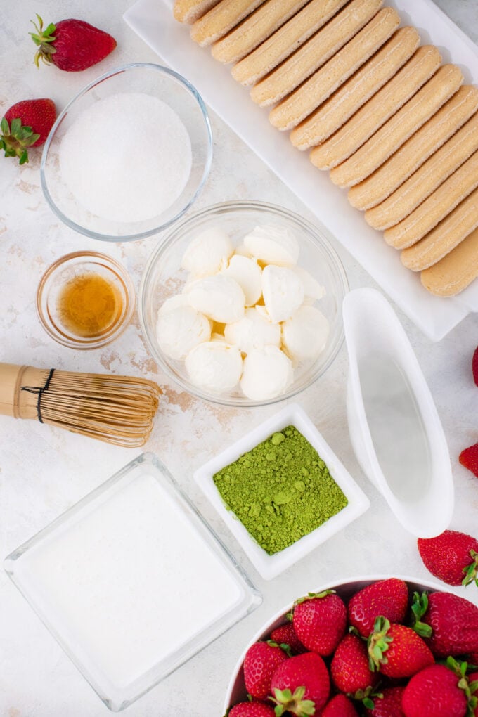Overhead shot of matcha strawberry tiramisu ingredients in bowls on a table.