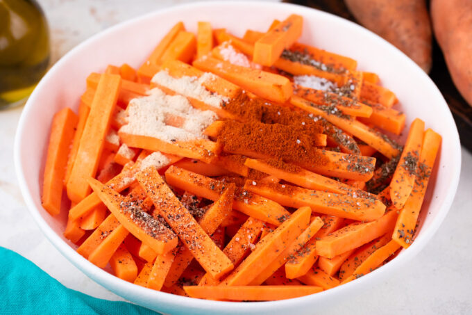 Seasoning sweet potato fries.