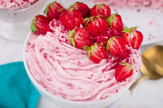 A bowl of strawberry whipped cream with fresh strawberries.