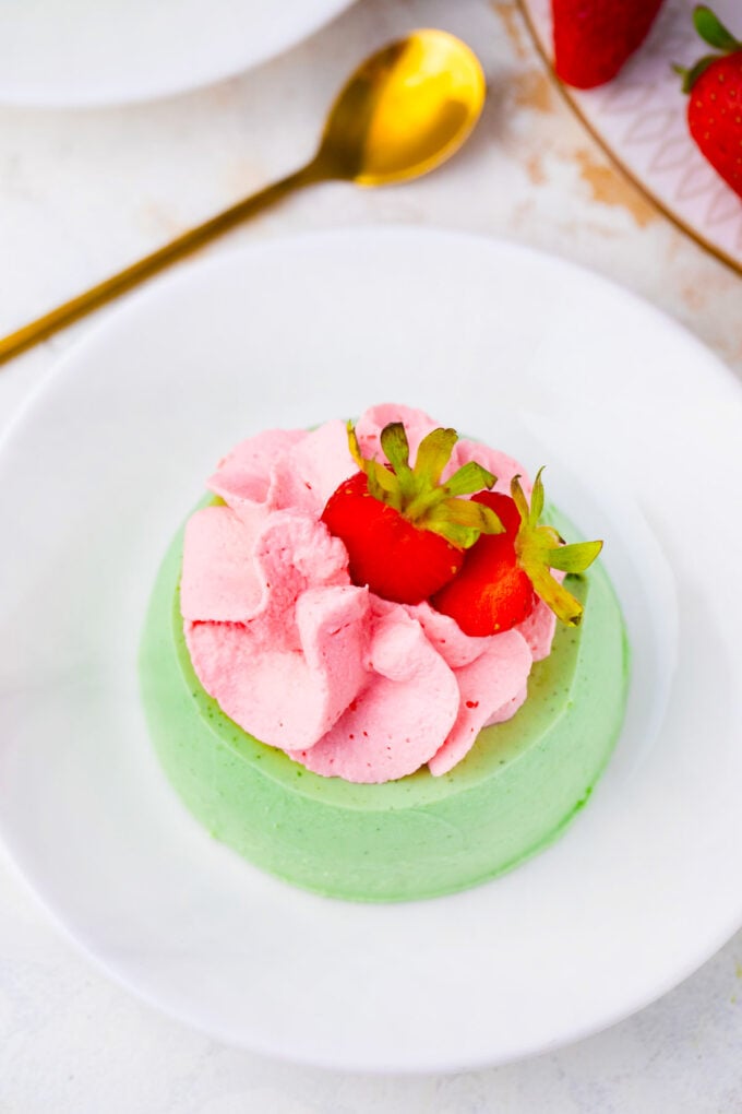 Overhead shot of matcha panna cotta topped with strawberry whipped cream.