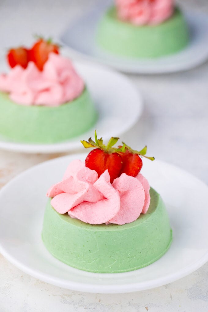 Green matcha panna cotta with strawberry whipped cream and fresh strawberries.