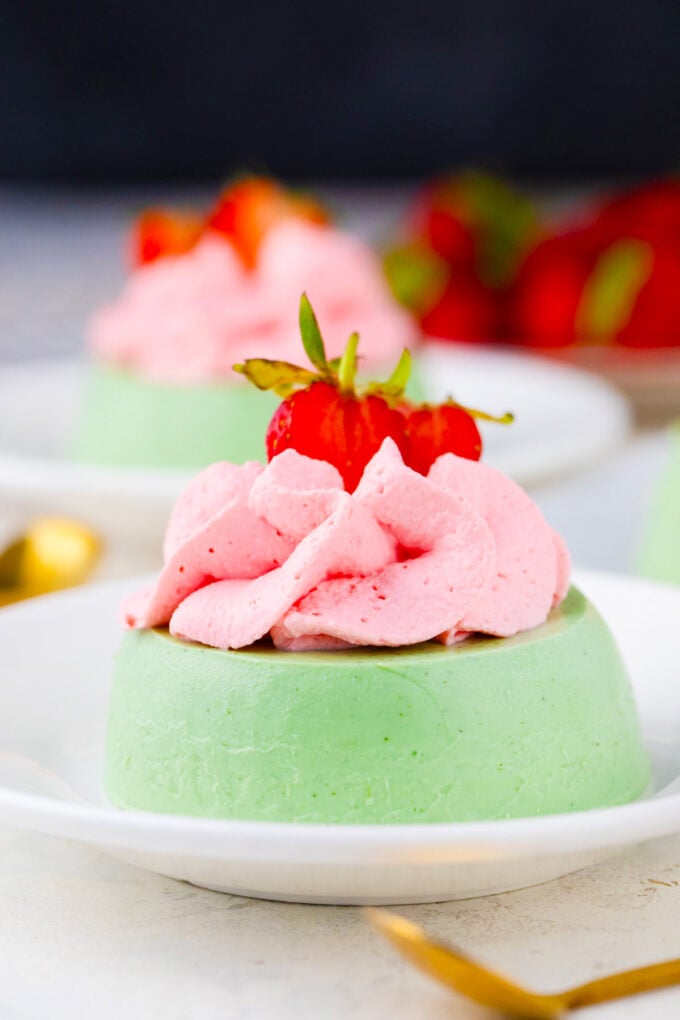 Green matcha panna cotta with pink strawberry whipped cream.