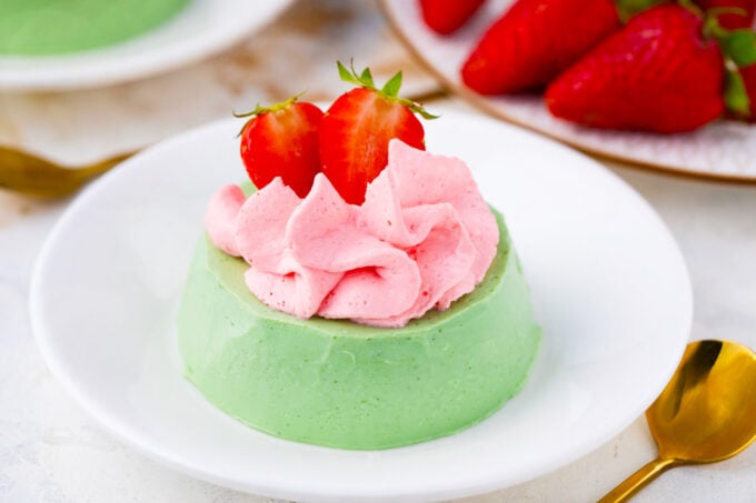 Green matcha panna cotta with strawberry whipped cream and fresh berries.
